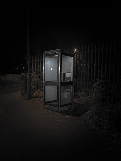 A mysterious old phone booth illuminated by a soft, eerie light at dusk.