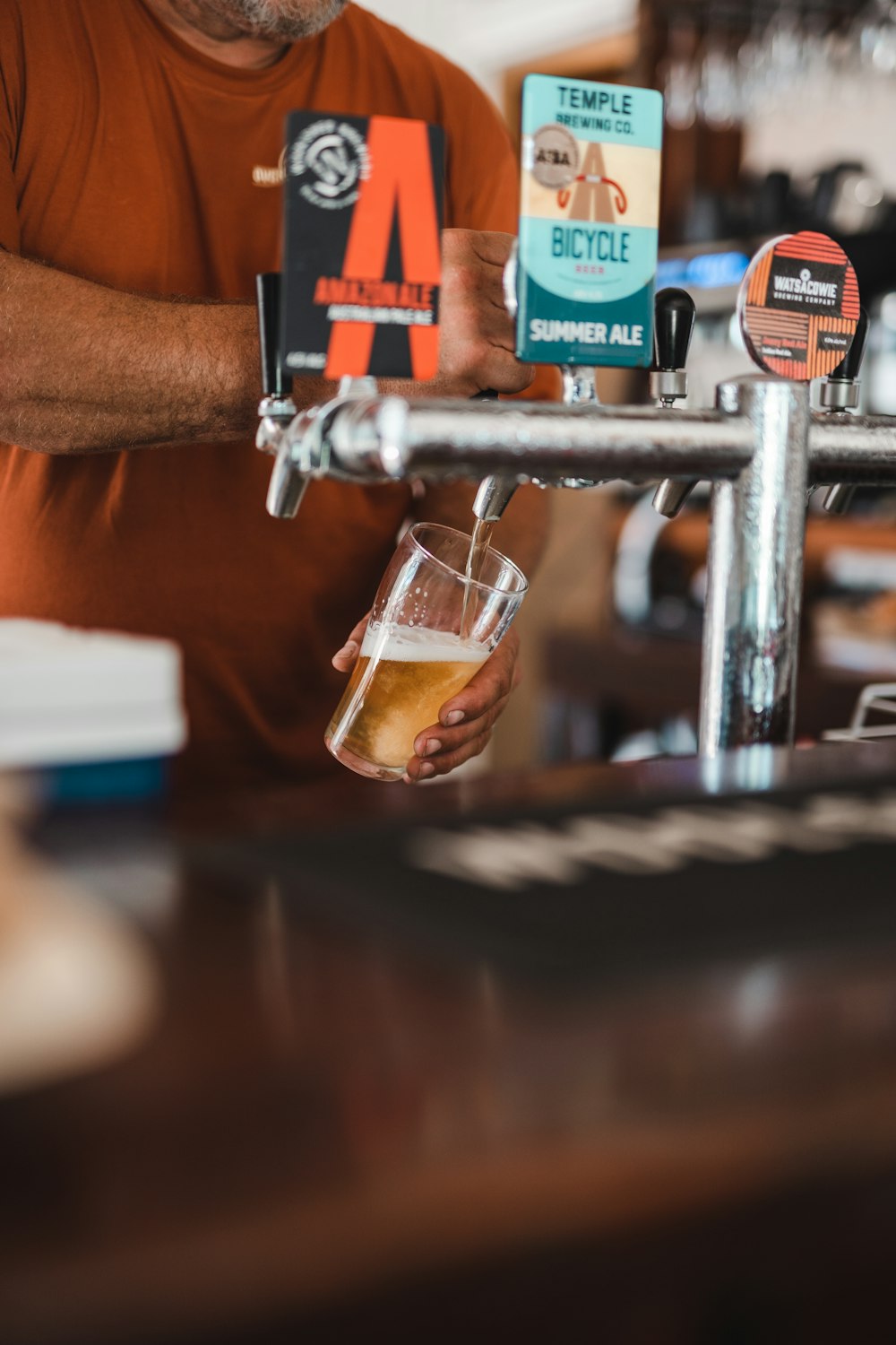 person pouring beer on clear drinking glass