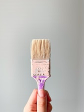 person holding brown and gray paint brush