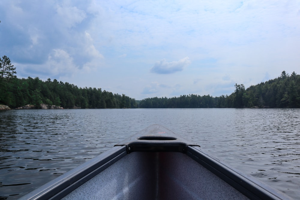 boat on lake near green trees under white clouds and blue sky during daytime