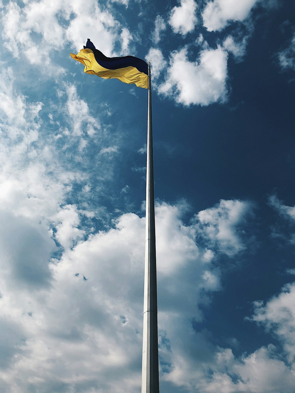 昼間の白い雲と青い空の下に黄色い旗
