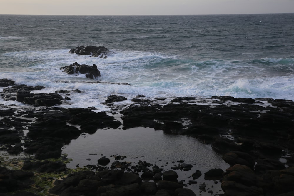 Rocas negras en la orilla del mar durante el día