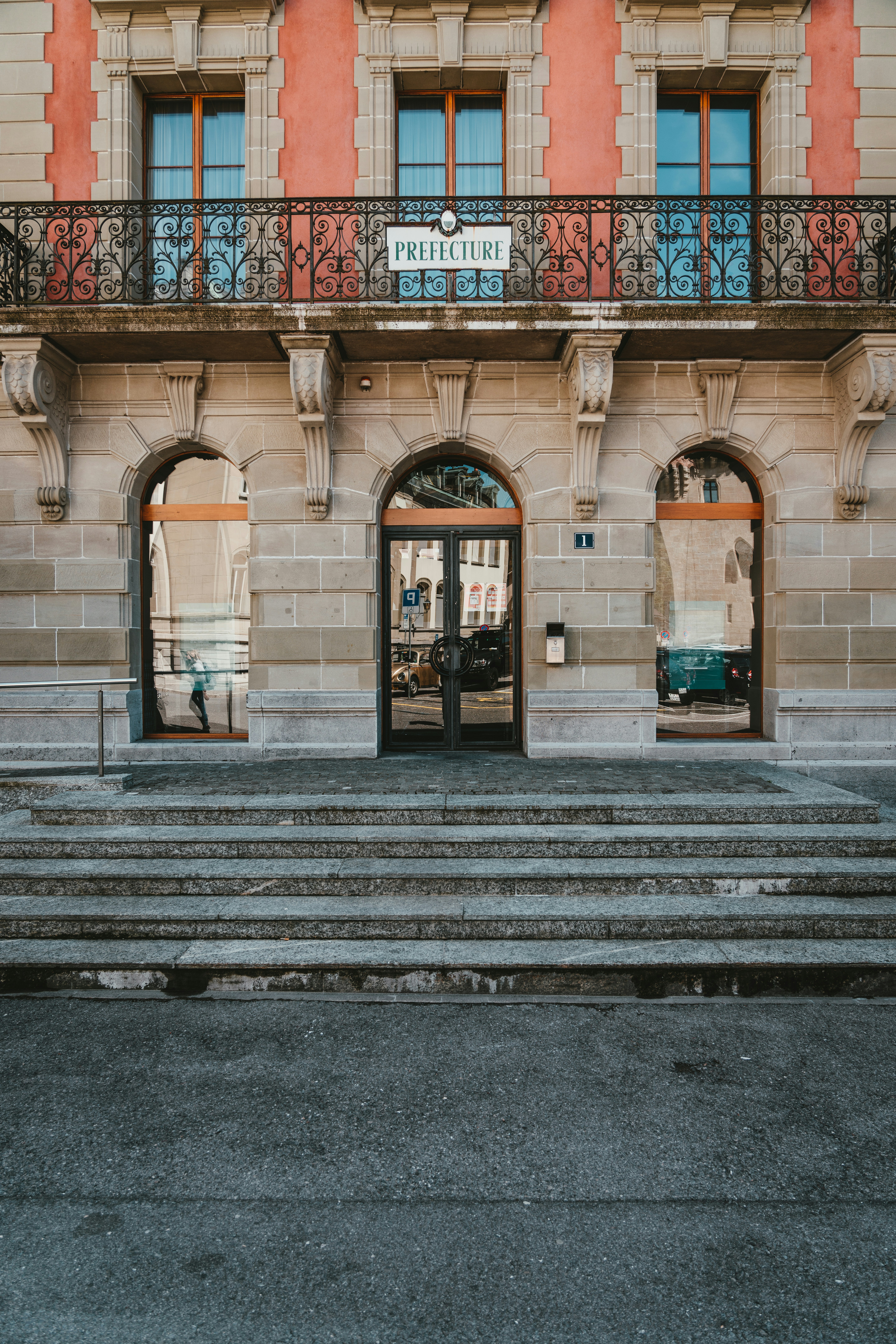 gray concrete building with red and white floral window curtain