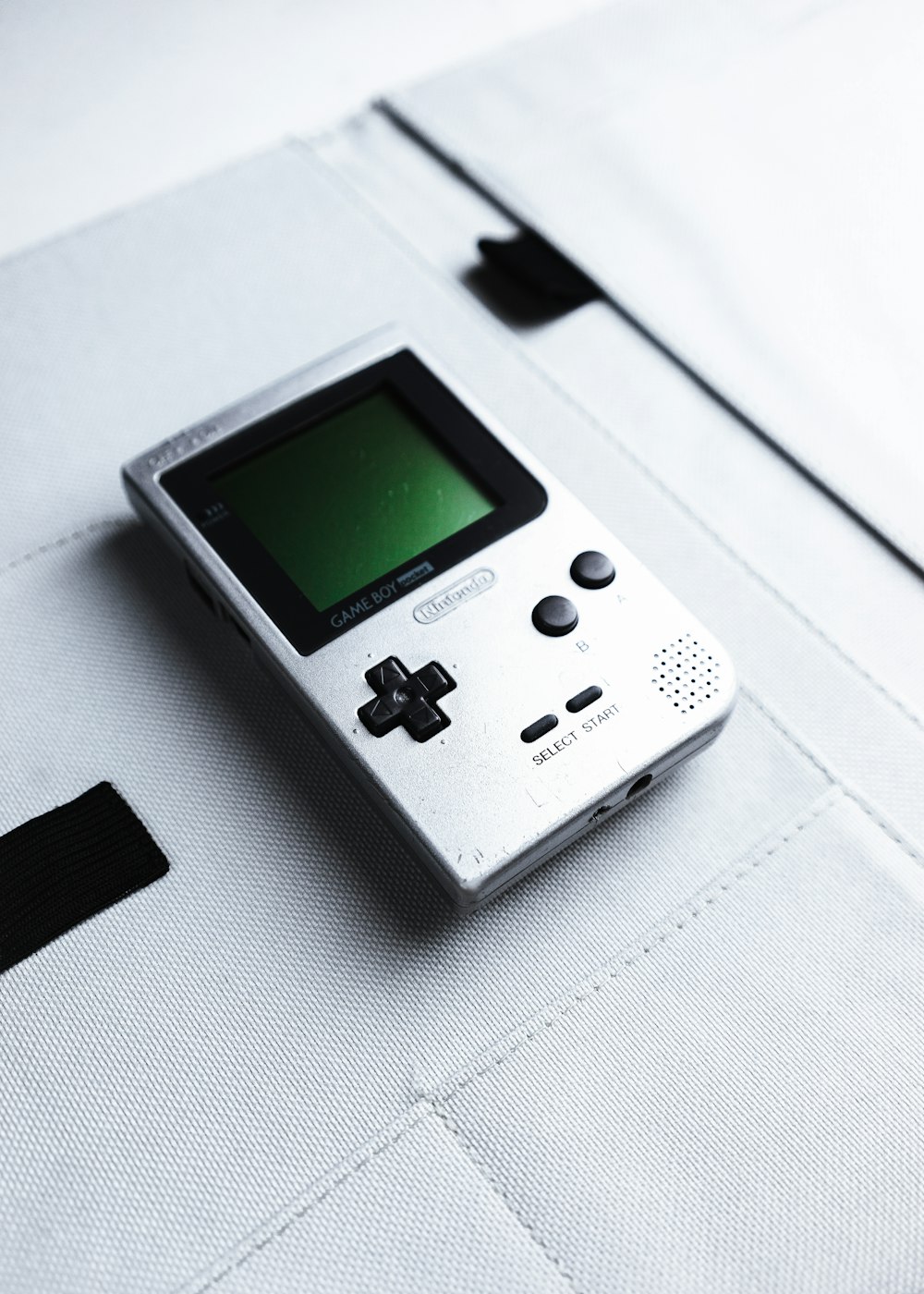 gray nintendo game boy on white textile