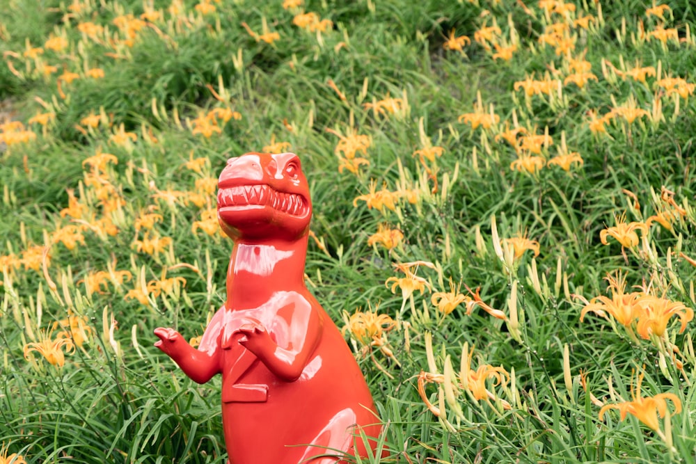 red frog figurine on green grass field during daytime