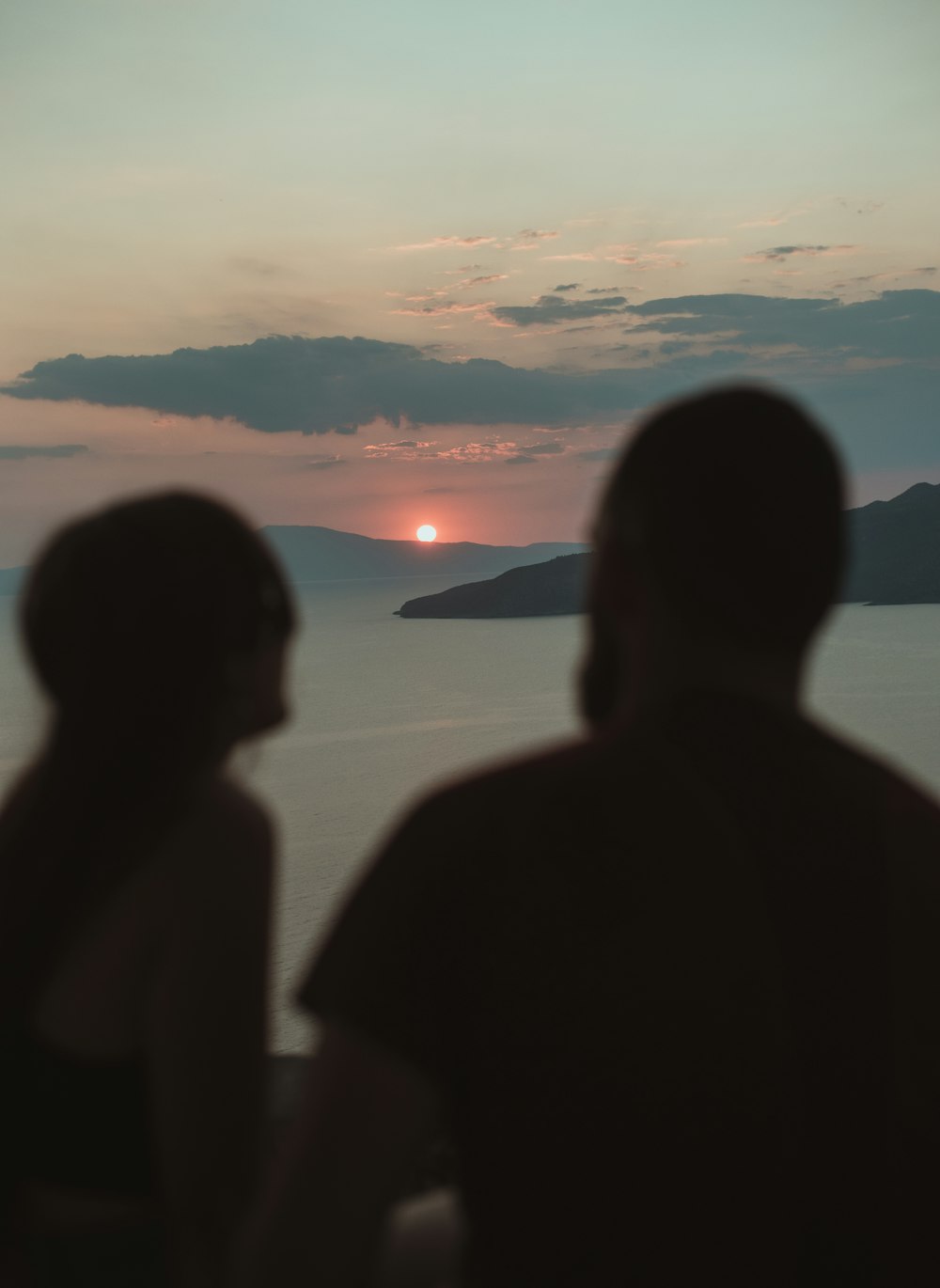Silueta de personas de pie en la orilla del mar durante la puesta del sol