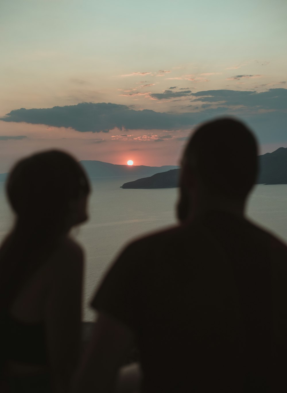 silhueta de pessoas em pé na costa durante o pôr do sol