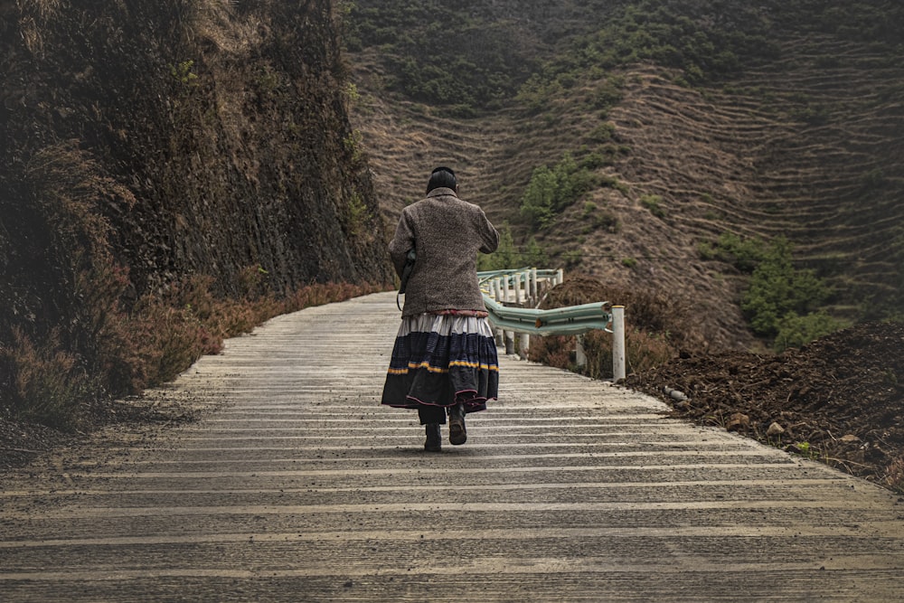 woman in black and white dress walking on wooden bridge during daytime