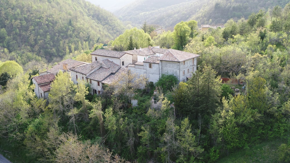 white and brown concrete house surrounded by green trees during daytime