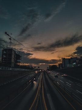 A wide view of a road under construction with heavy machinery at work during sunset.
