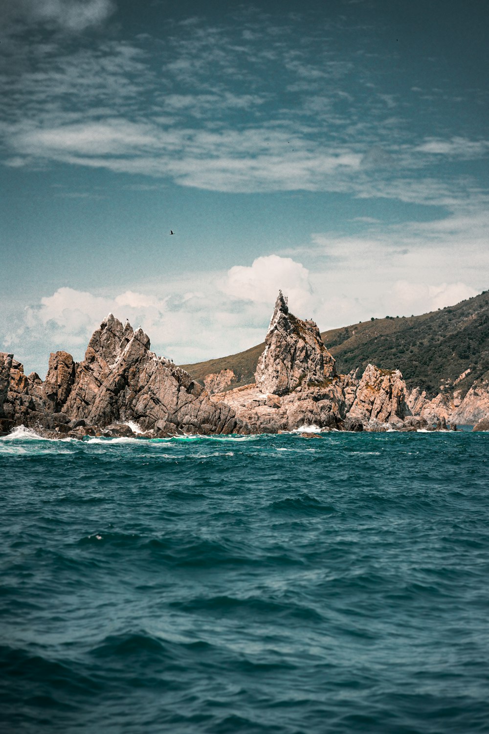 brown rock formation on blue sea under blue sky during daytime