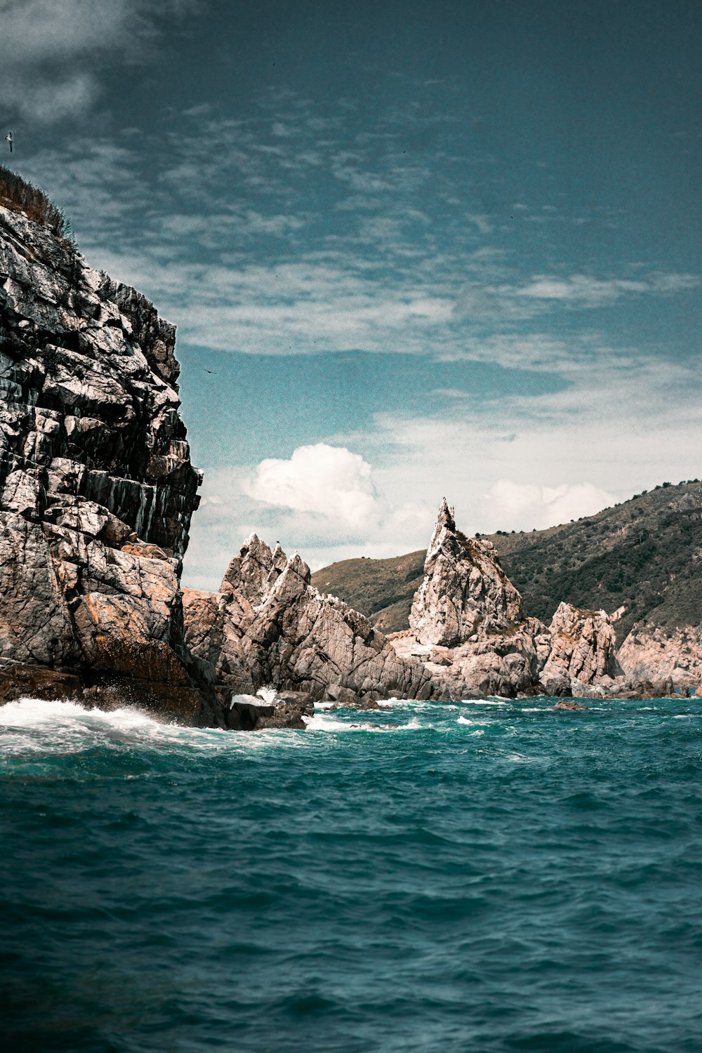 gray rocky mountain beside blue sea under blue sky during daytime