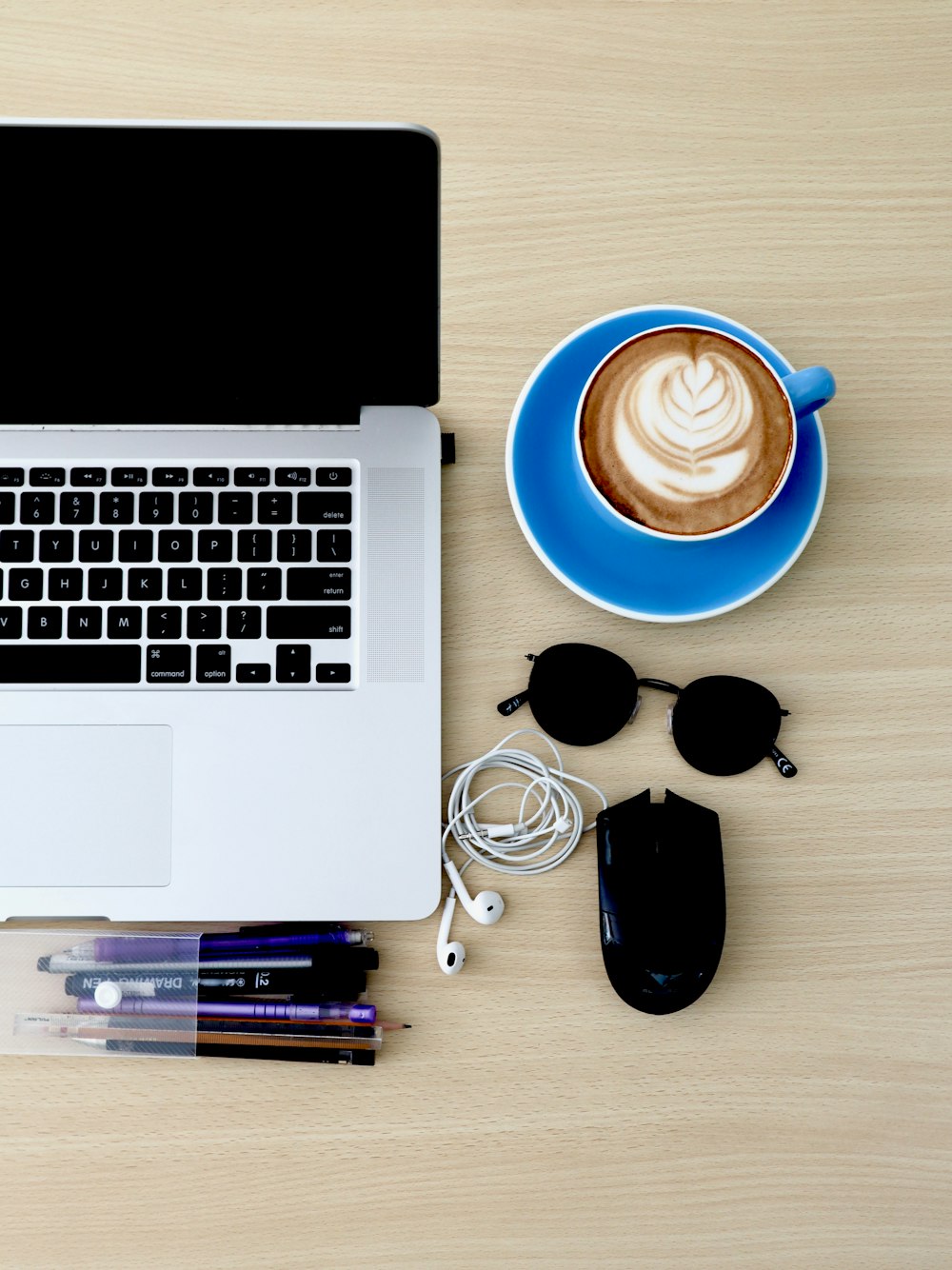 white and blue ceramic mug beside black leather pouch and black sunglasses