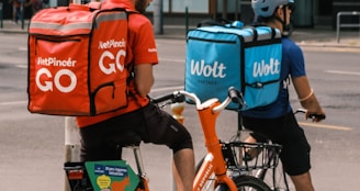 man in orange shirt and blue denim shorts riding on bicycle