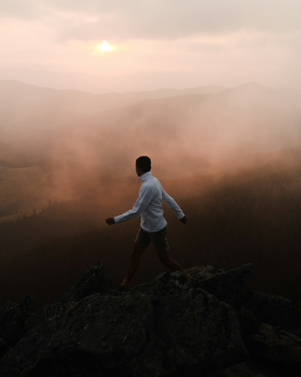 man in white long sleeve shirt sitting on rock during daytime