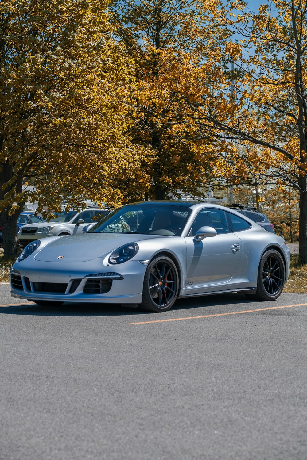 Porsche 911 prata estacionado em estrada de concreto cinza perto de árvores verdes durante o dia