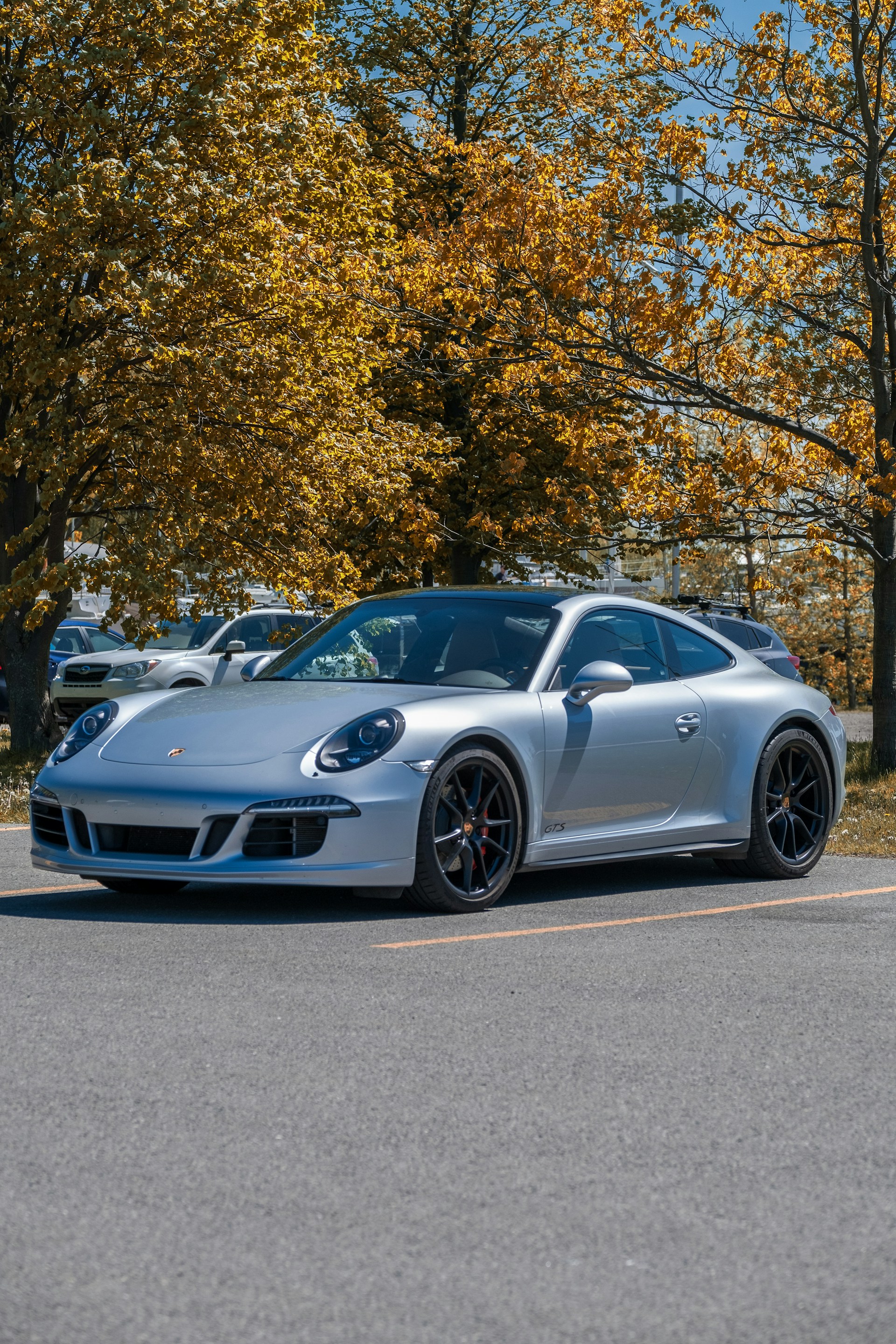 silver porsche 911 parked on gray concrete road near green trees during daytime