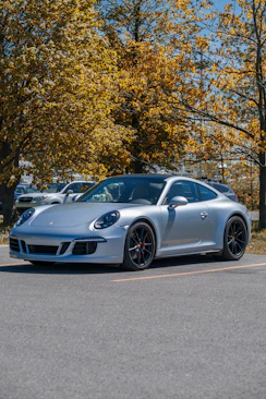 silver porsche 911 parked on gray concrete road near green trees during daytime