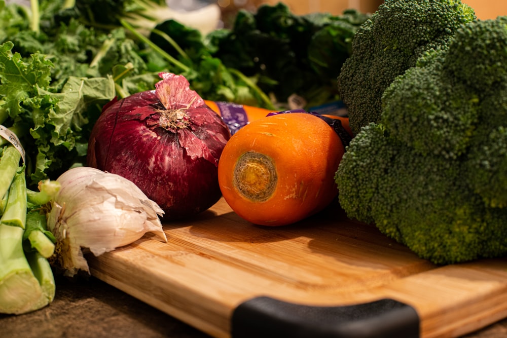 red tomato beside green vegetable on brown wooden chopping board