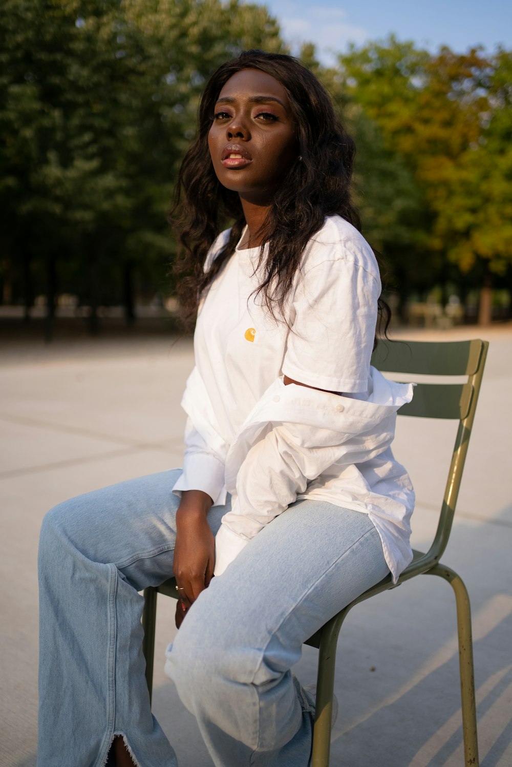 woman in white dress shirt and blue denim jeans sitting on brown wooden chair