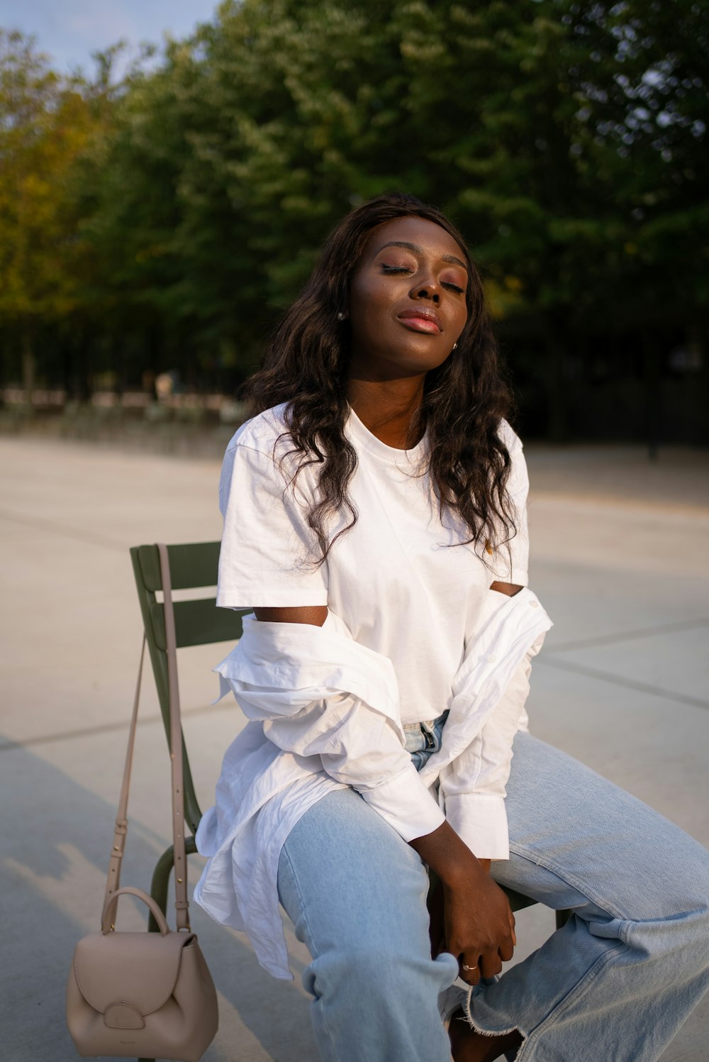 woman in white long sleeve shirt and blue denim jeans sitting on gray concrete bench during