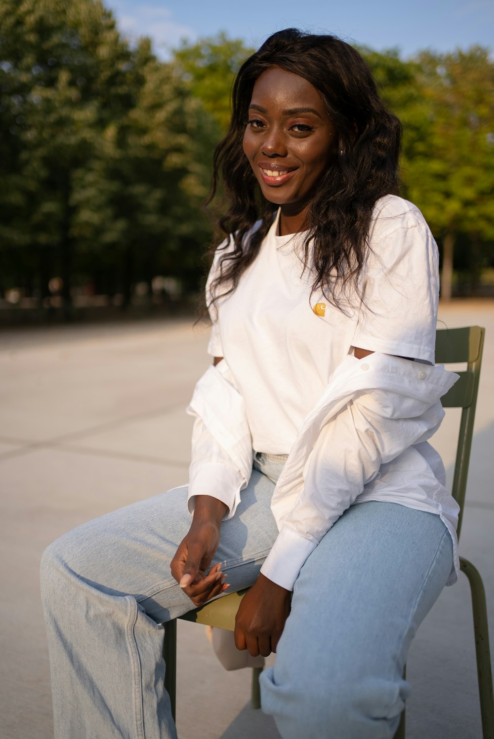 woman in white dress shirt and blue denim jeans sitting on bench