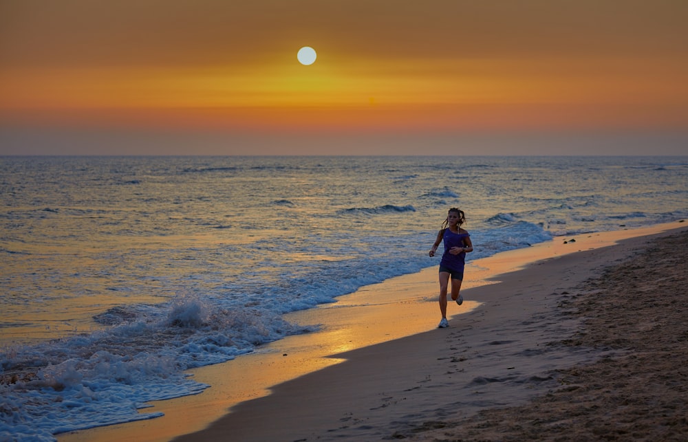 woman in black dress walking on beach during sunset