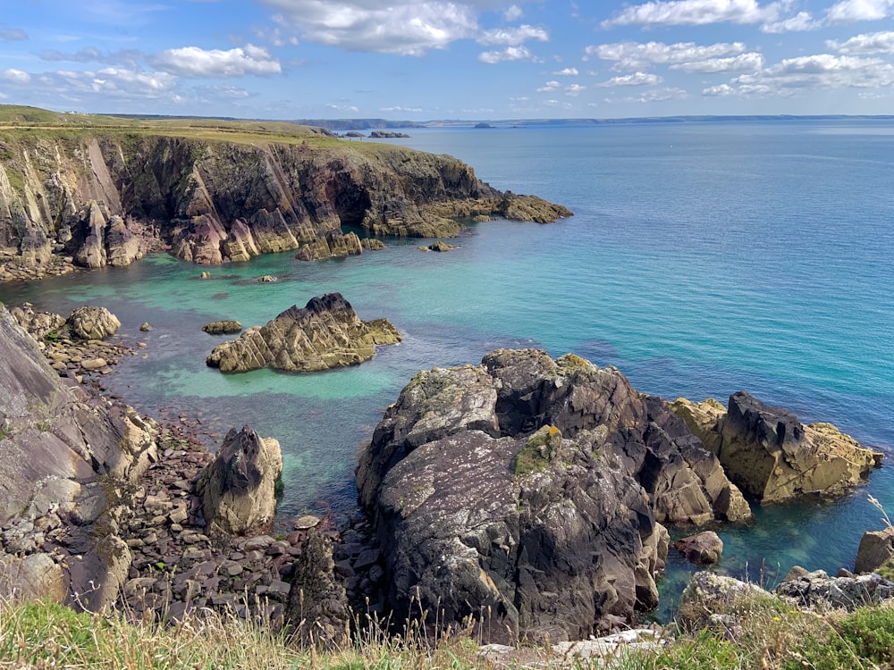 brown rocky mountain beside blue sea under blue sky during daytime