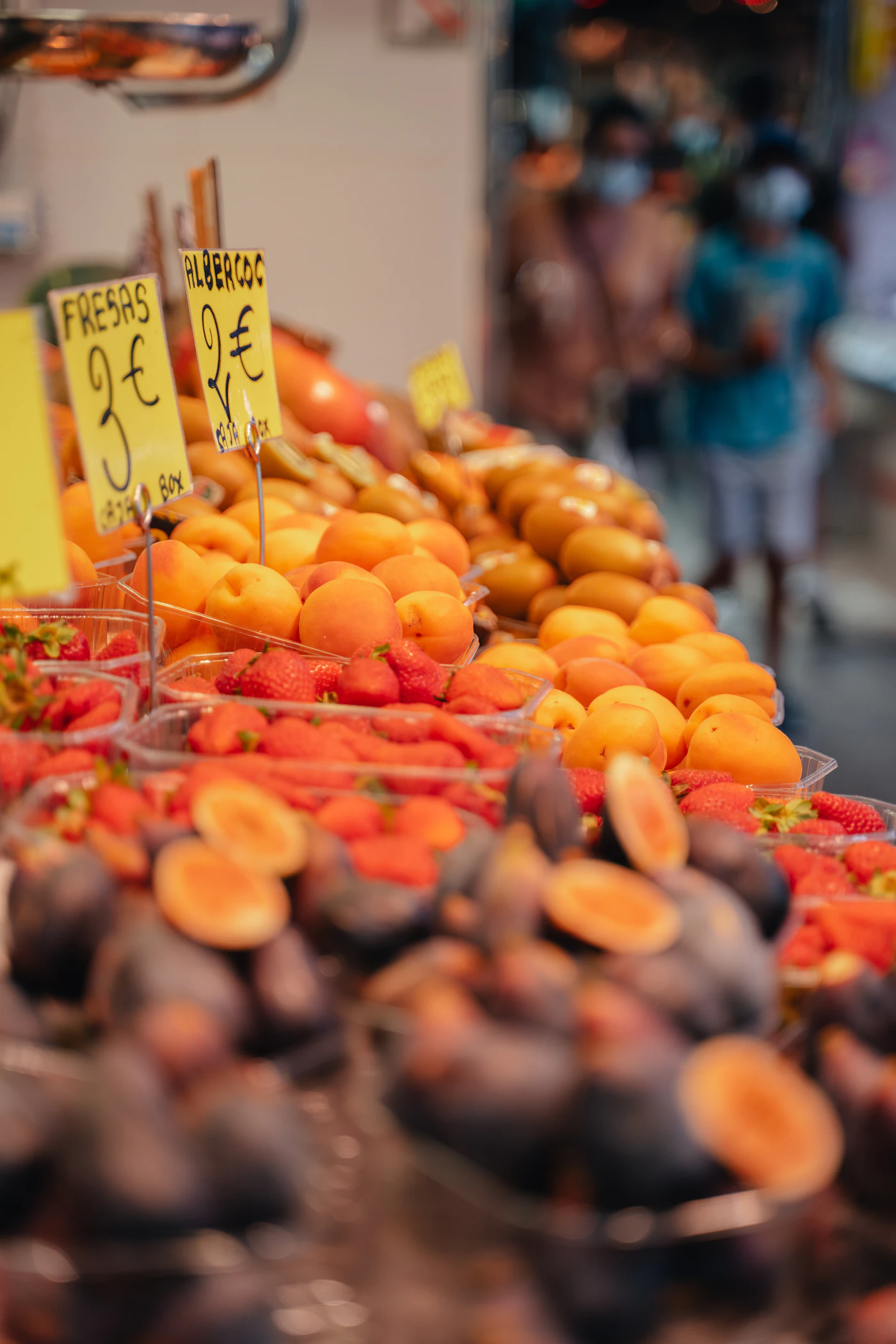 Close-up of apricots, strawberries and halved figs on a market stall with handwritten price signs