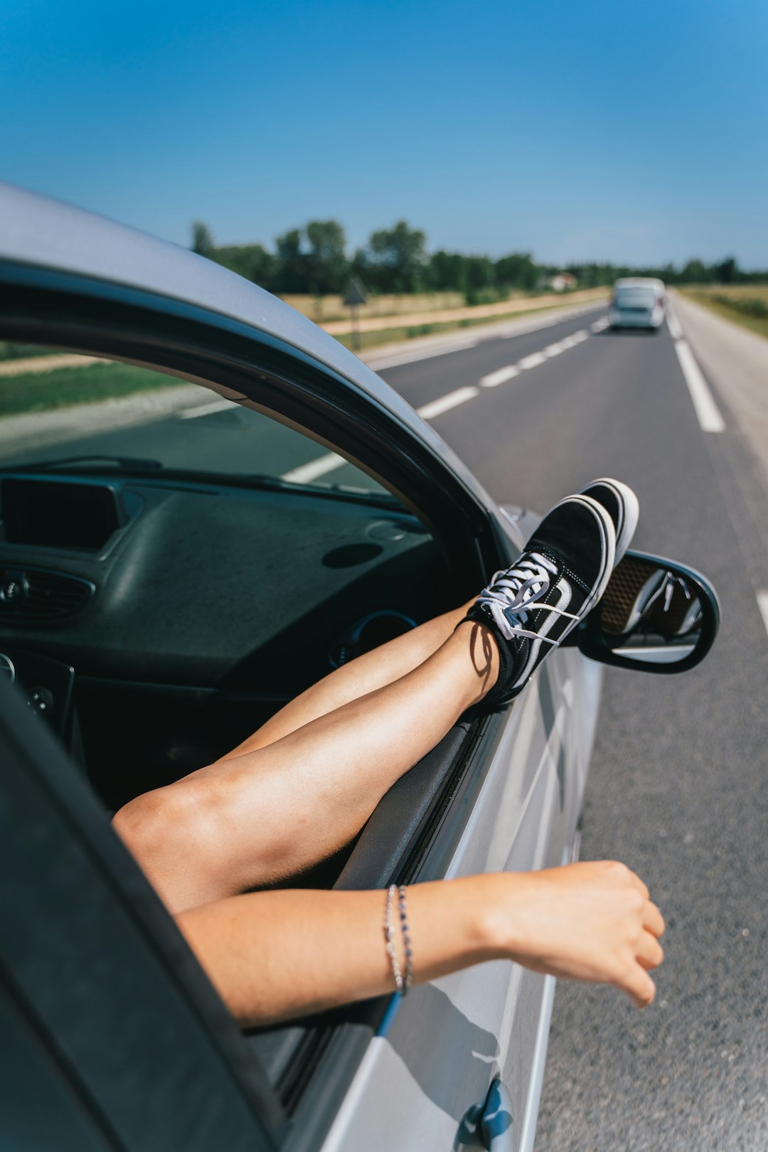 woman in black and white sneakers driving car