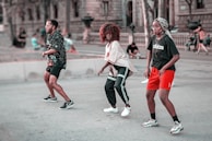 2 women in red and black jersey shirt running on gray concrete road during daytime