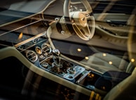 A luxurious car interior featuring a meticulously designed dashboard with chrome accents and a high-end steering wheel. The gear shift is prominently displayed, surrounded by elegant controls and dials. The seating is crafted from premium leather, with visible stitching for added detail.