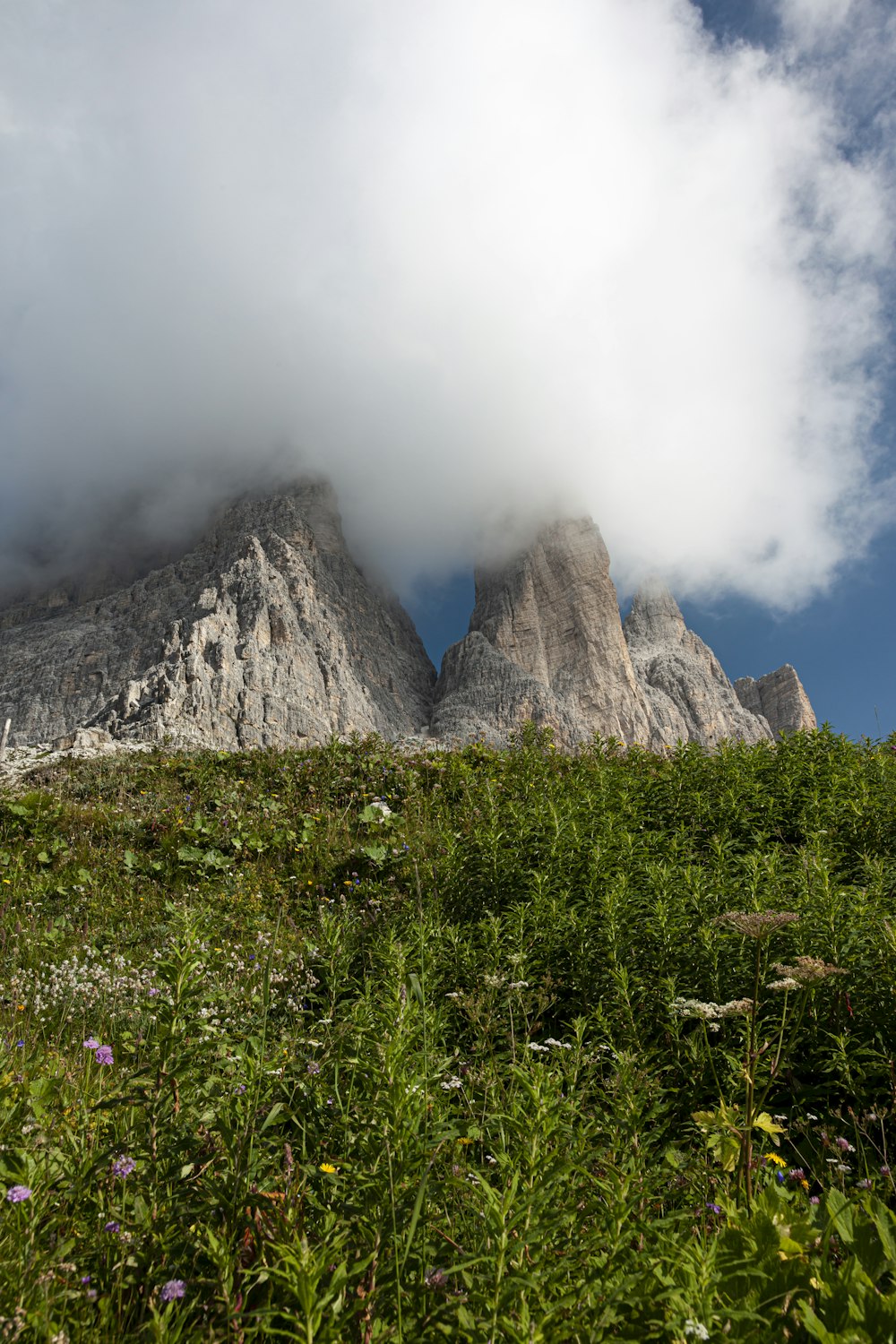 green grass field near gray mountain under white clouds during daytime