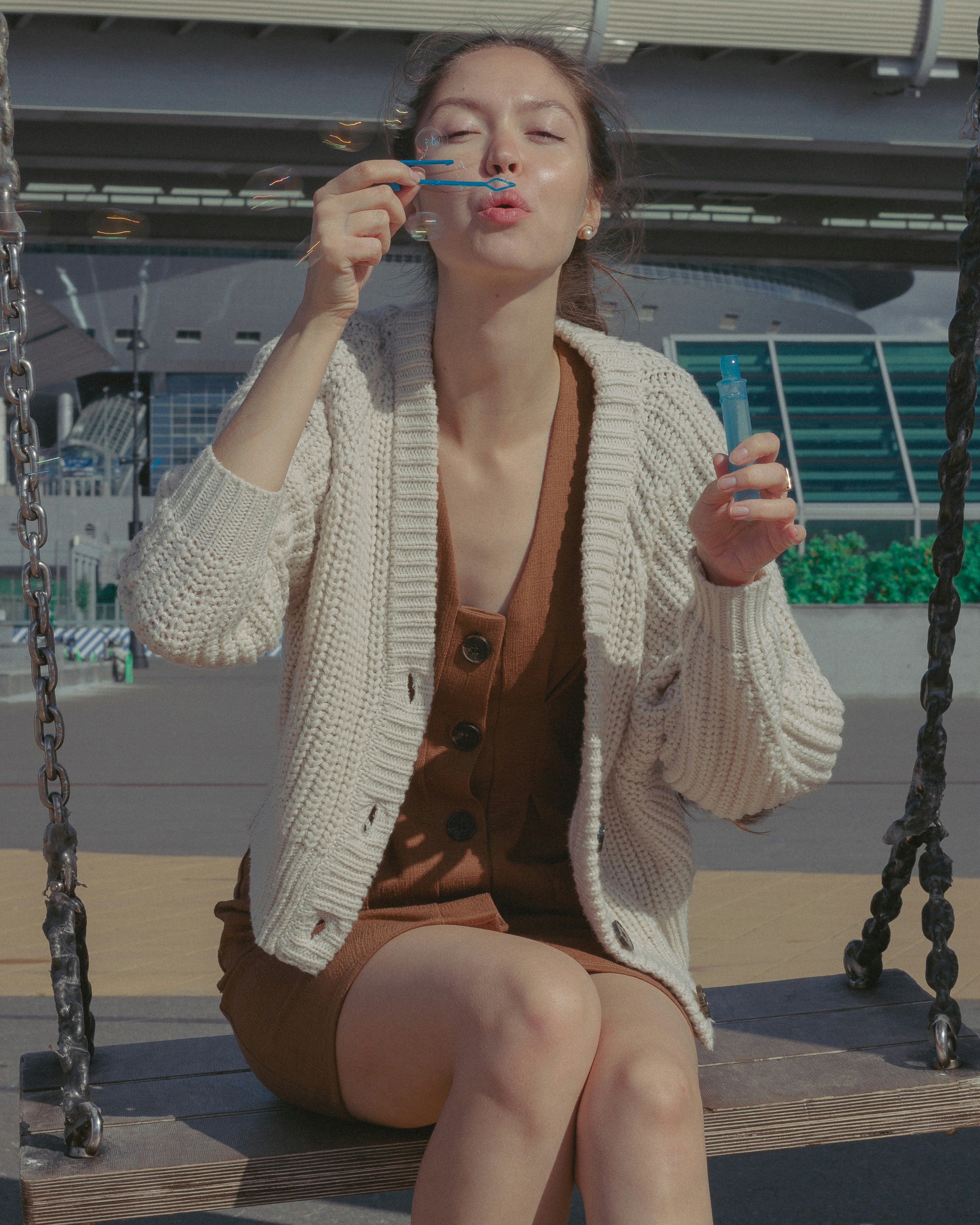 woman in white cardigan sitting on swing