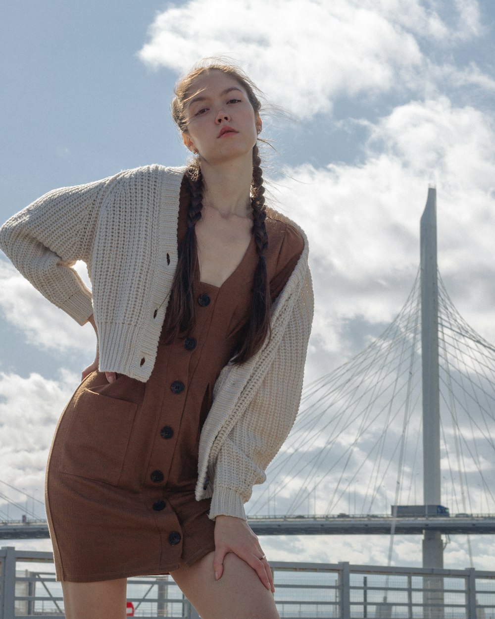 woman in white and brown pinstripe dress shirt and brown pants standing near bridge during daytime
