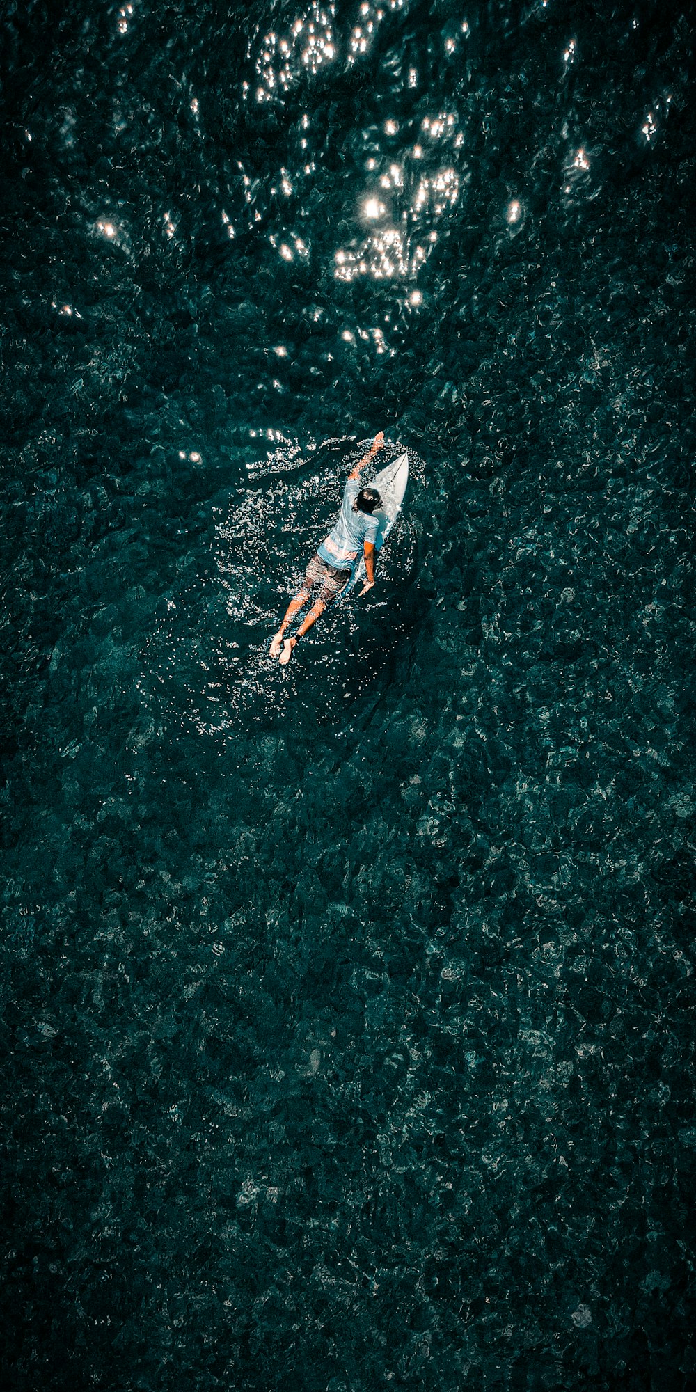 man in white shirt and blue shorts surfing on water during daytime