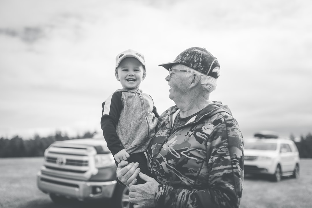 grayscale photo of boy in camouflage jacket and cap