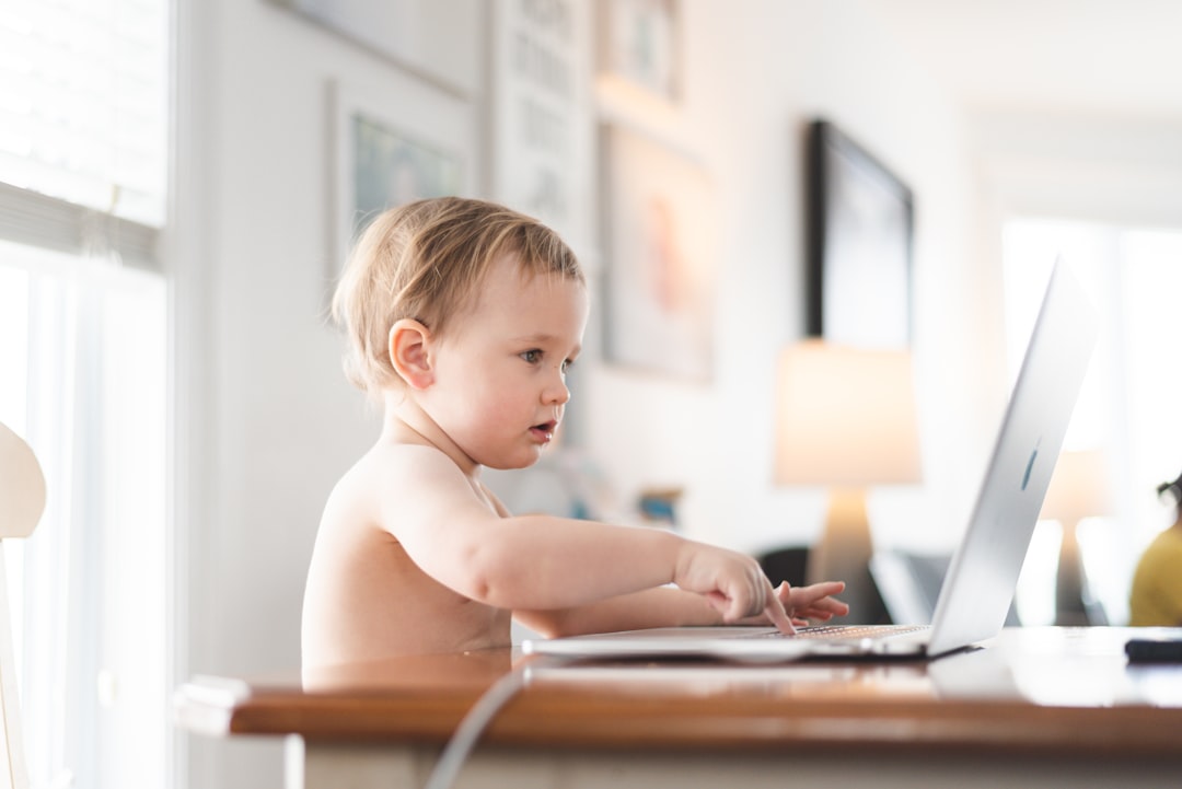 topless boy sitting on chair using laptop computer