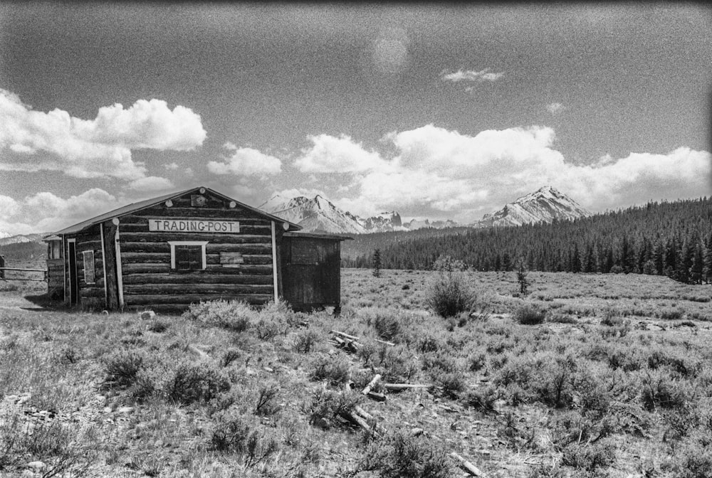 grayscale photo of wooden house near trees