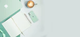 An overhead shot of a cream white desk with a mocha beige cwtch bag, a coffee cup, and scattered notes.