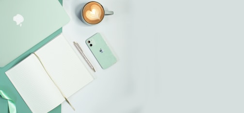 Overhead view of a slate-colored table with notebooks, tablets, and coffee cups neatly arranged