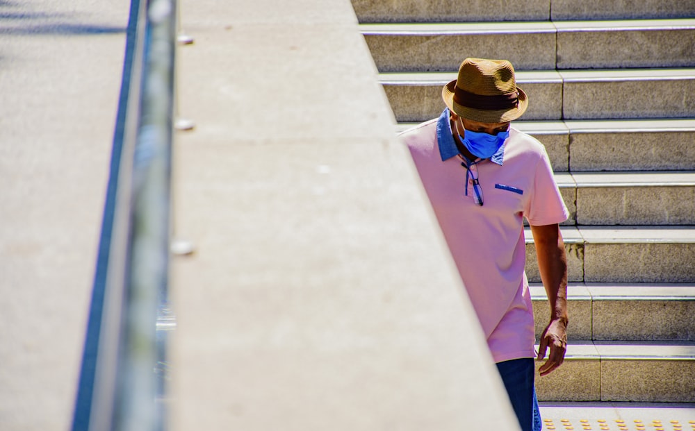 woman in blue polo shirt and brown hat standing on gray concrete stairs during daytime