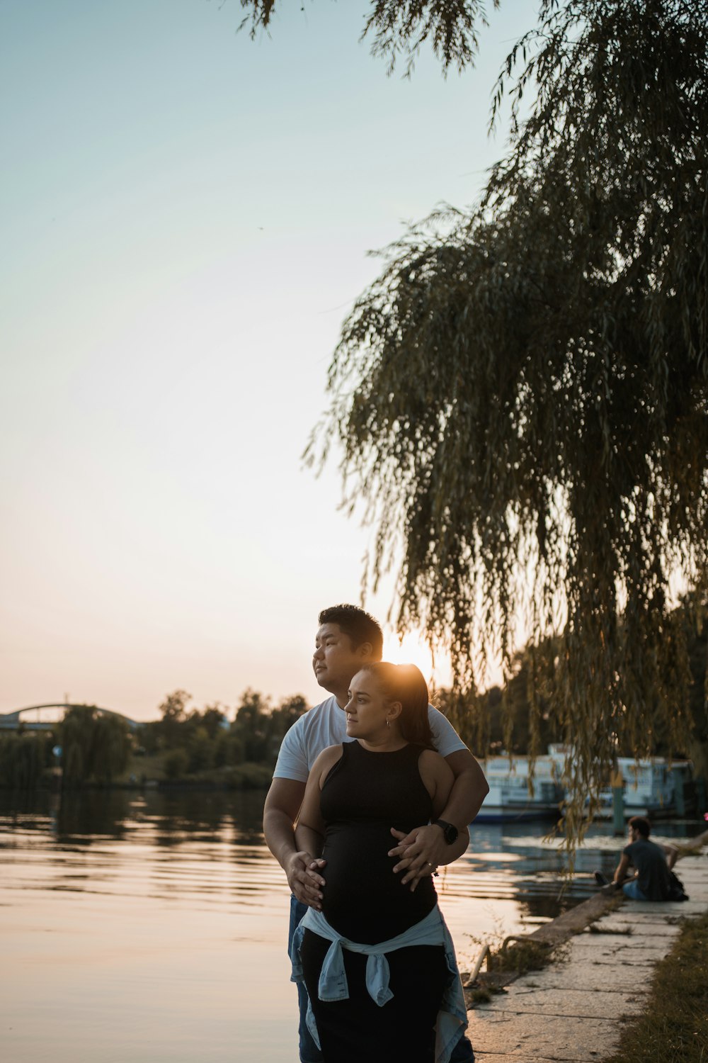 man in white crew neck t-shirt sitting on brown wooden dock during daytime