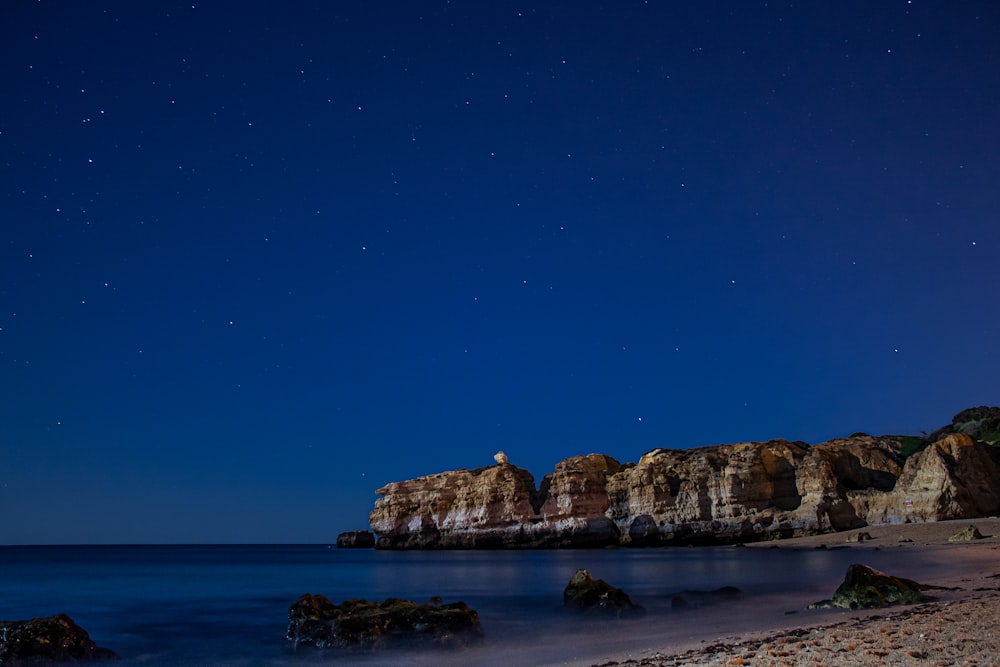 brown rock formation on blue sea under blue sky during daytime