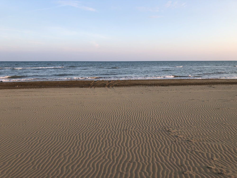 brown sand near body of water during daytime