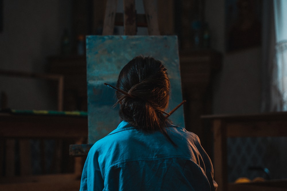 woman in blue shirt standing near brown wooden cabinet