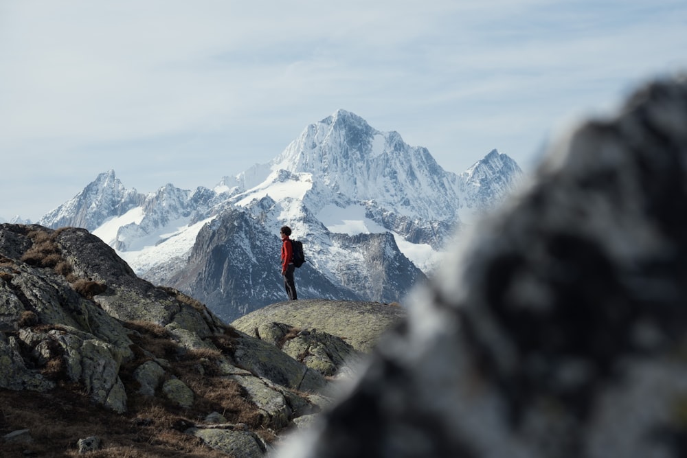 person in red jacket standing on rock mountain during daytime