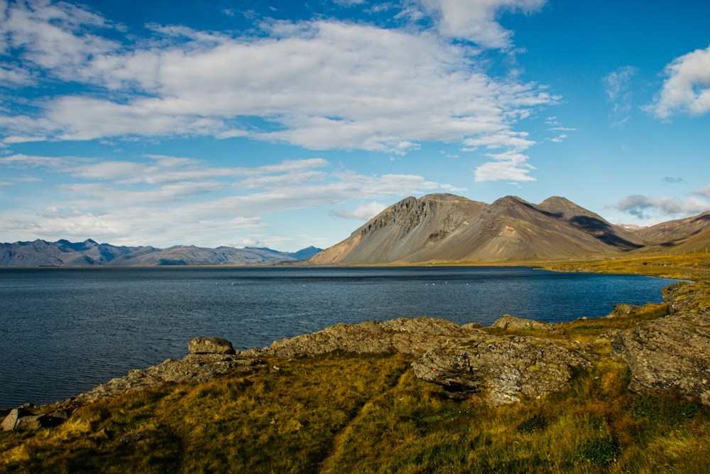 green mountain near body of water under blue sky during daytime