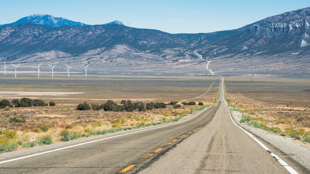 gray concrete road near green grass field and mountains during daytime