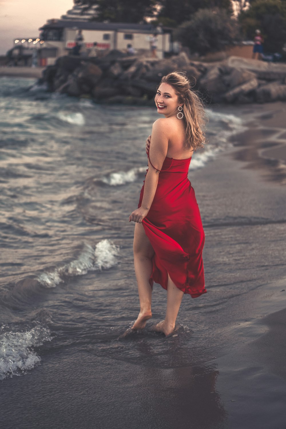 woman in red spaghetti strap dress standing on beach during daytime